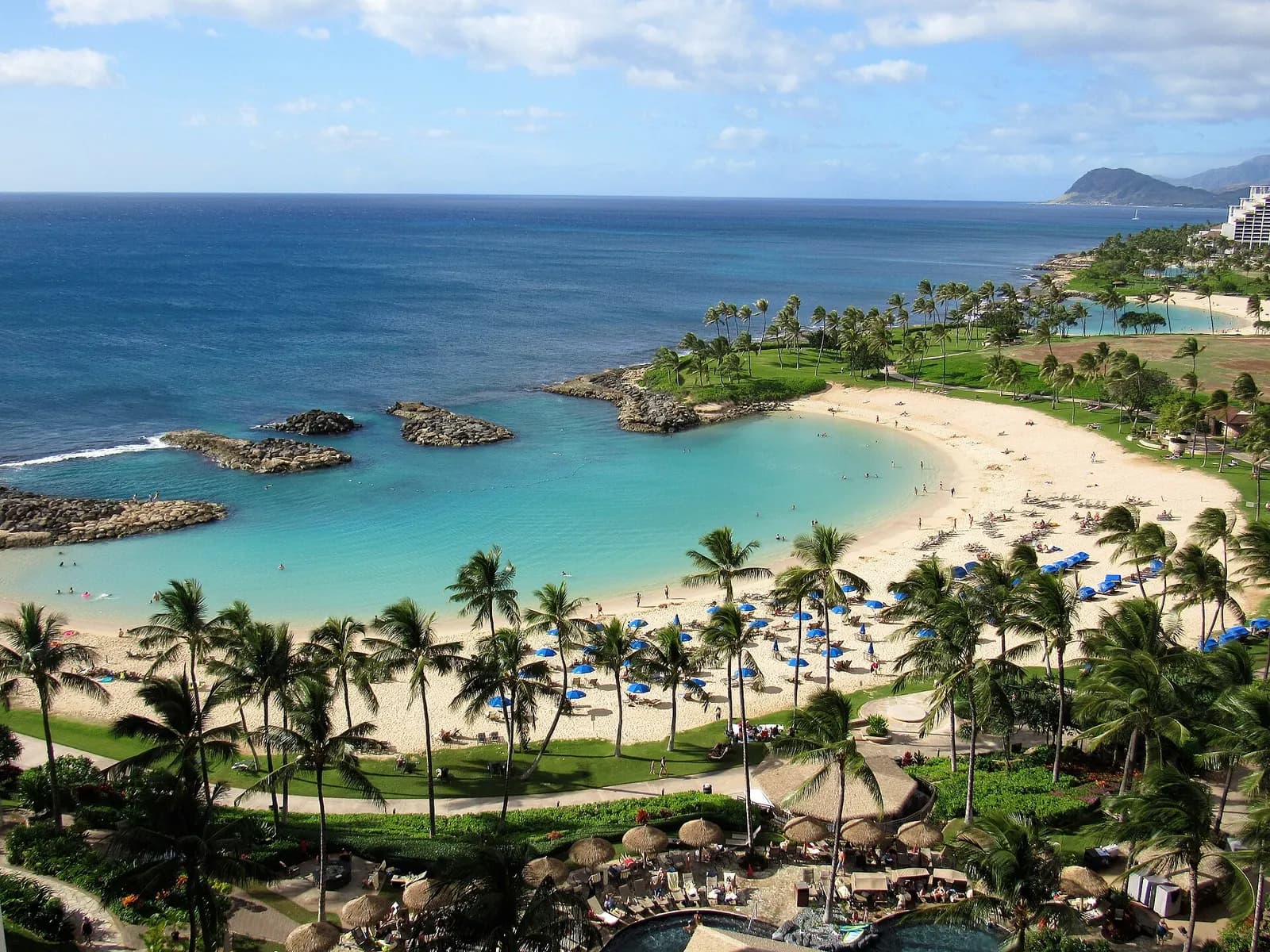 Một hồ ở Ko Olina với các tòa nhà khu nghỉ dưỡng, hàng cọ và bãi cát